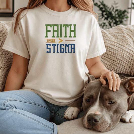 Woman wearing Faith Over Stigma tee in Ivory sitting on couch with grey bully breed dog