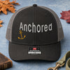 Anchored embroidery trucker hat in black and charcoal flatlay with Holy Bible, dog leash, and autumn leaves