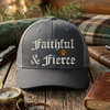 Black/Gray cap with 'Faithful & Fierce' text on a wooden surface with outdoor items.
