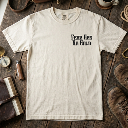 Ivory t-shirt with 'Fear Has No Hold' text on a wooden surface with outdoor gear.