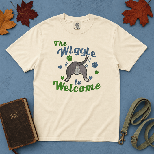 Ivory Comfort Colors tee with embroidered wiggle butt bully breed design, flatlay on blue background with Bible and leash