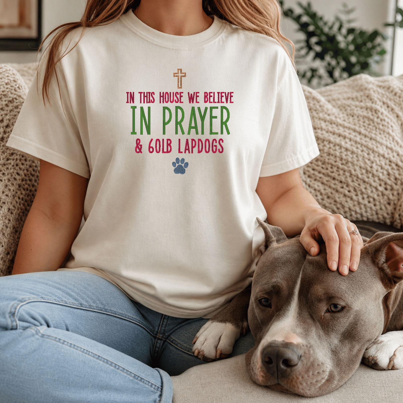 Woman wearing In This House We Believe in Prayer and 60lb Lapdogs tee in Ivory sitting with bully breed dog