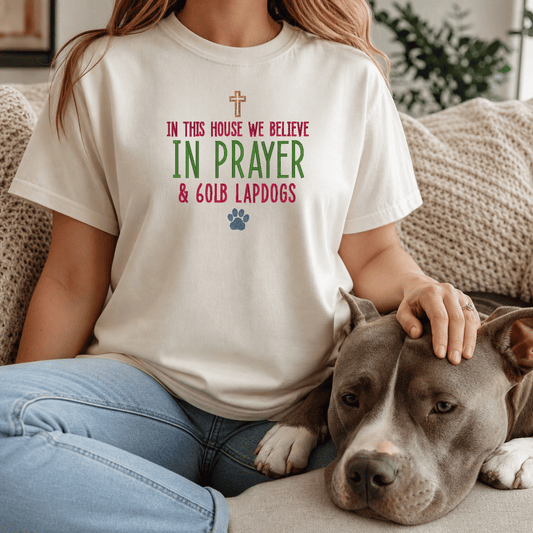 Woman wearing In This House We Believe in Prayer and 60lb Lapdogs tee in Ivory sitting with bully breed dog