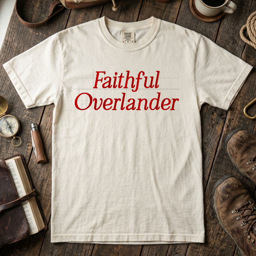 Ivory t-shirt with 'Faithful Overlander' text on a wooden surface with travel-themed items.
