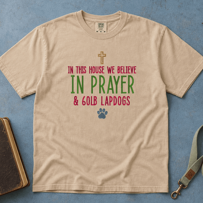 In This House We Believe in Prayer and 60lb Lapdogs Comfort Colors Tee in Sandstone flatlay with Holy Bible and dog leash