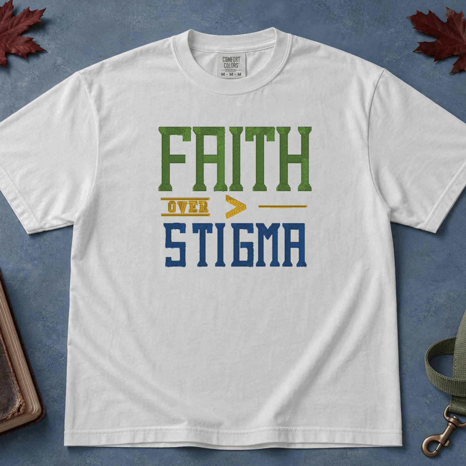 Faith Over Stigma Comfort Colors Tee in White flatlay with dog leash on blue background with autumn leaves