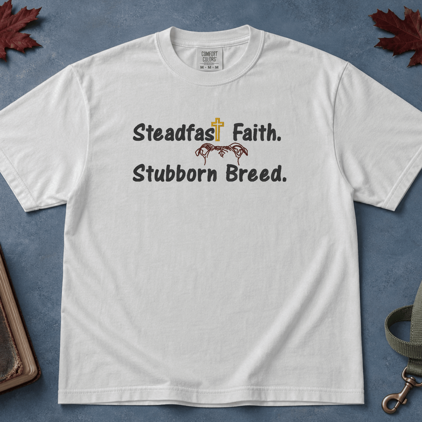 Steadfast Faith Stubborn Breed Comfort Colors Tee in White flatlay with Holy Bible and dog leash