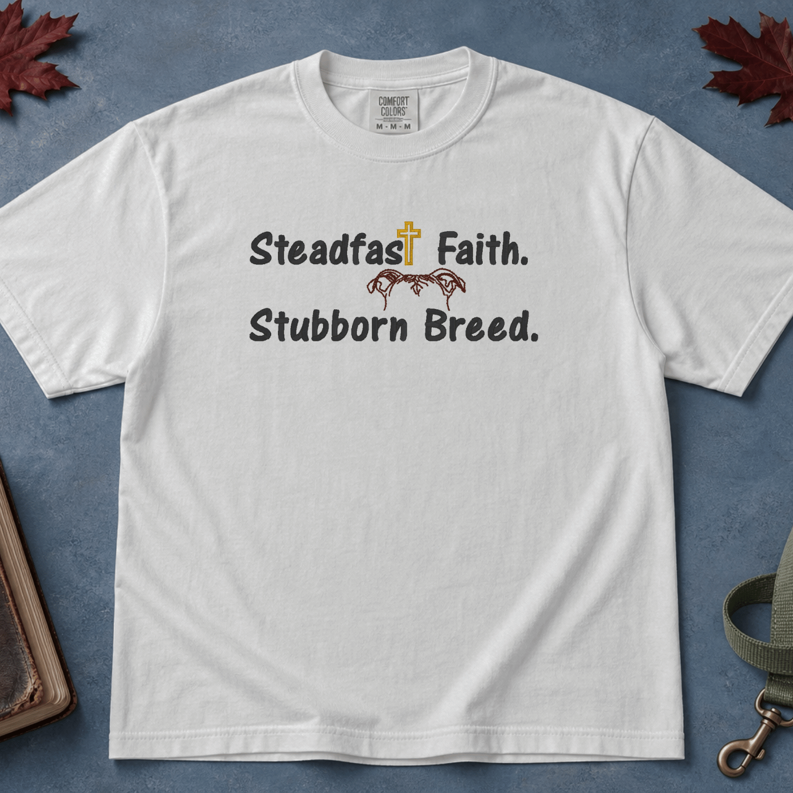 Steadfast Faith Stubborn Breed Comfort Colors Tee in White flatlay with Holy Bible and dog leash