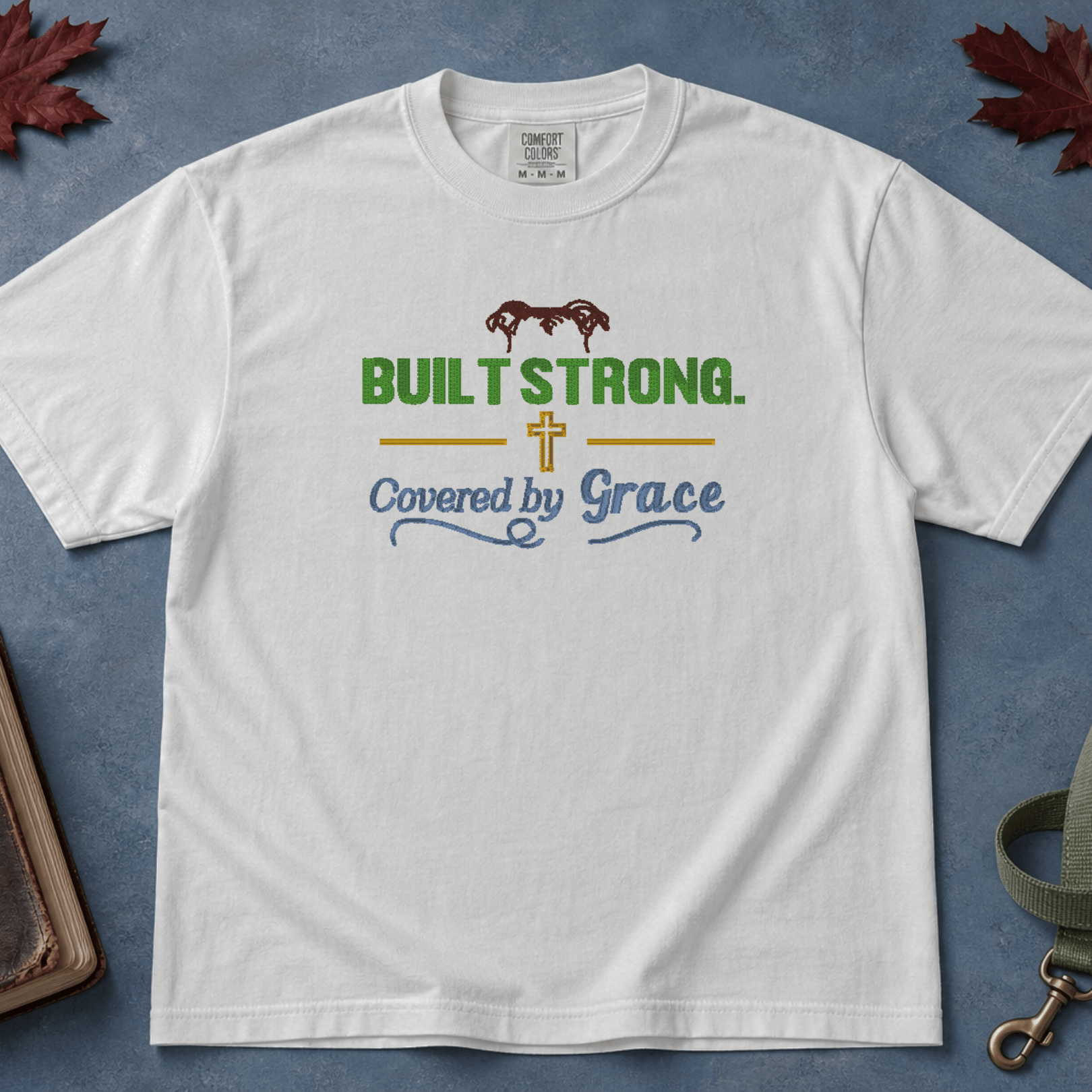 Built Strong Covered by Grace Comfort Colors Tee in White flatlay with autumn leaves and dog leash