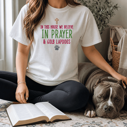 Woman wearing In This House We Believe in Prayer and 60lb Lapdogs tee in White sitting with open Bible and bully breed dog