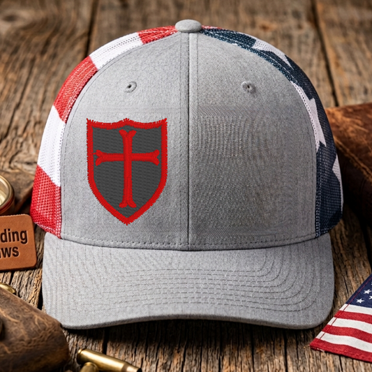 Gray cap with red emblem on a wooden surface with American flag and leather items.