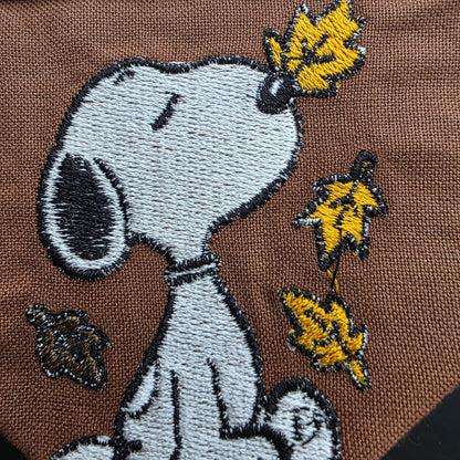 Close-up of white dog and yellow leaves embroidered on brown bandana